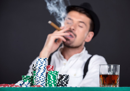 Man is playing poker in casino. Gambling chips, cigar and a glass of whiskey.の写真素材