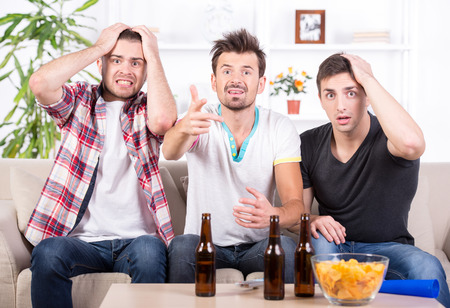 Group of sports fans watching game on TV at home.の写真素材