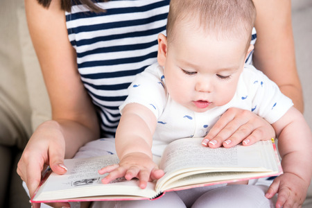 Mother reading a book to little baby son.の写真素材