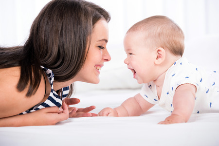 Beautiful mother and son are lying in bed and looking at each other.