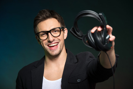 Portrait of a smiling young man with headphones on the dark background.の写真素材