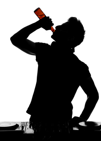 Portrait of a young DJ with mixer at the work, is drinking alcohol.の写真素材