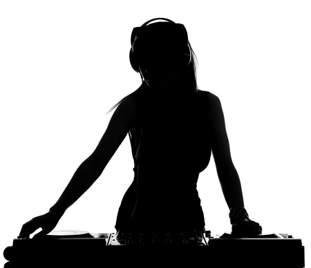 Beautiful male DJ with her headphones is standing at her deck mixing sound.の写真素材