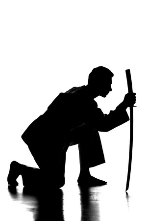Silhouette of martial arts man is standing with a sword, isolated on the white background.の写真素材