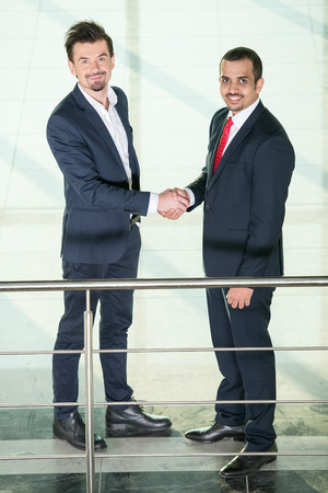 Business partners are shaking hands as a symbol of unity and looking at the camera.の写真素材