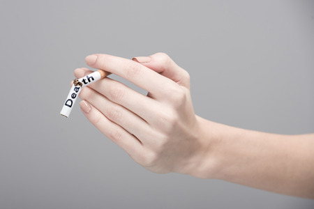 Close-up female hand is holding a broken cigarette.