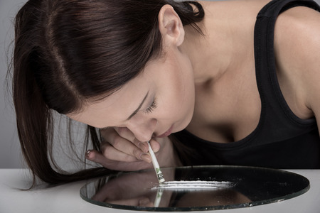 Addicted young woman is sniffing lines of drugs.の写真素材