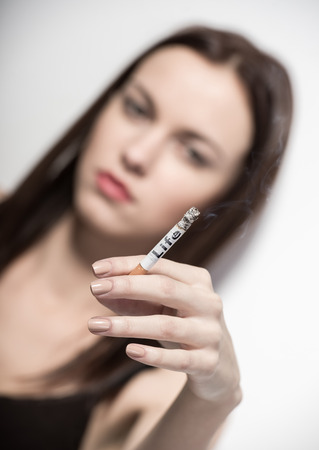 Beautiful woman is smoking a cigarette, isolated on gray background.の写真素材