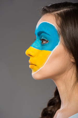 Flag of Ukraine painted on the face of the young beautiful woman.の写真素材