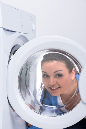 Smiling housewife is doing laundry with washing machine at home.の写真素材