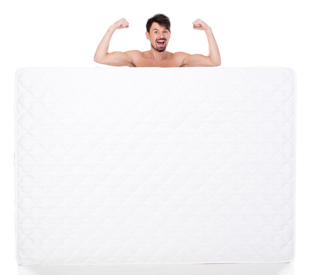 Young man with a white mattress isolated on white background.の写真素材