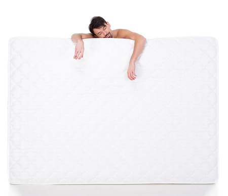 Young man with a white mattress isolated on white background.の写真素材