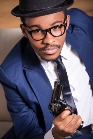 Young black man is wearing suit and hat with gun.の写真素材