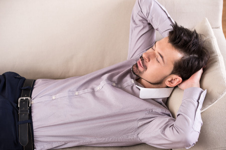 Tired businessman is sleeping on the sofa at the office.