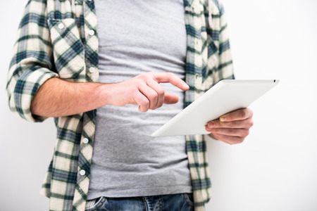 Casual young man is holding a touch pad tablet PC