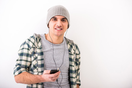 Casual young man with mobile phone and  headphone, on grey .の写真素材