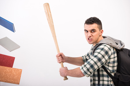 Young man with wooden baseball bat and books, on grey .の写真素材