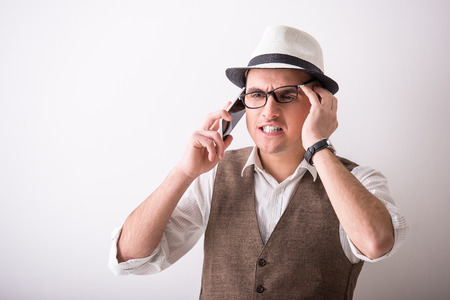 Portrait of  young confident man is wearing a hat is talking by phone on grey background.の写真素材