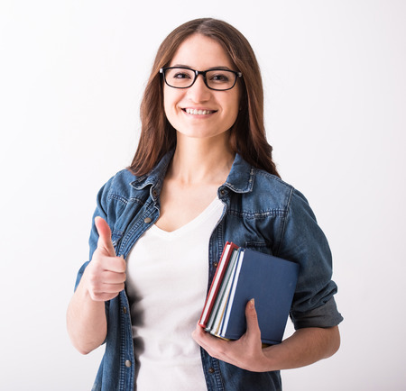 Portrait of a young woman with books on grey background.の写真素材