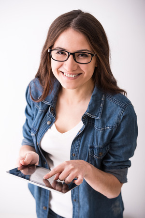 Portrait of a young woman with tablet on grey background.の写真素材
