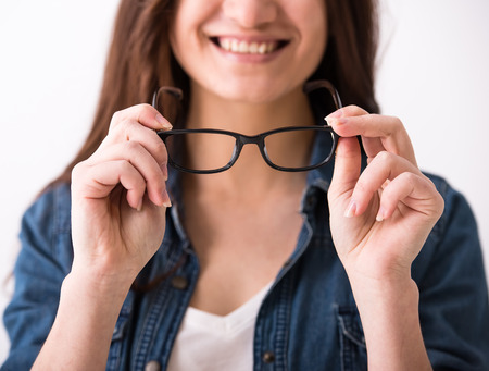 Portrait of a young woman with glasses on grey background.の写真素材