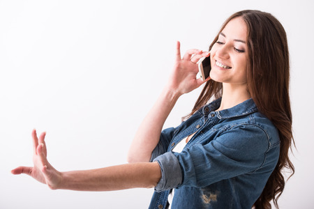 Portrait of a young woman is talking by phone and looking at her hand, new manicure.