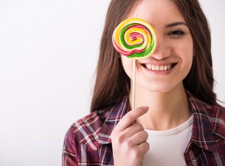 Beautiful playful young woman with colorful lollipop on grey .の写真素材