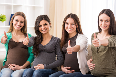 Portrait of four happy pregnant women are looking at the camera.の写真素材