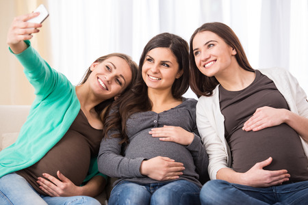Three happy pregnant women are making selfie photo.の写真素材