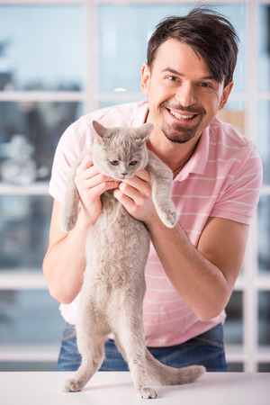 Smiling man with a cute cat is looking at the camera.の写真素材