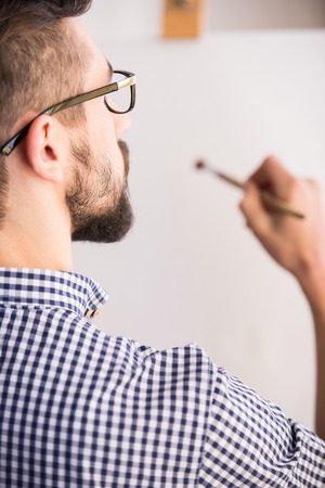 Back view of young man is painting on a canvas. Close-up.の写真素材