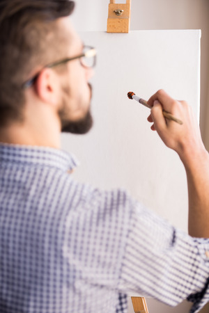 Back view of young man is painting on a canvas. Close-up.の写真素材