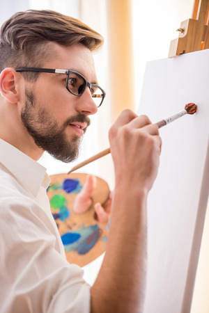 Side view of young artist  with brush and palette is going to painting a picture.の写真素材