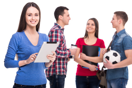 Education and people concept. Smiling female student with tablet. Her friends on background with coffee, textbooks and ball.の写真素材