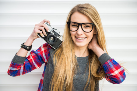Close-up of trendy girl face in sunglasses with vintage camera.の写真素材