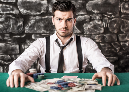 View of young, confident, gangster man in shirt and suspenders, while he's playing poker game.の写真素材