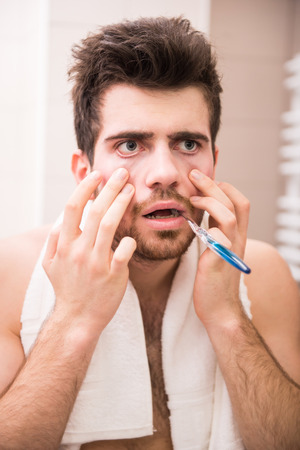 Morning routine of washing the teeth. Tired young man is brushing teeth with toothbrush.の写真素材
