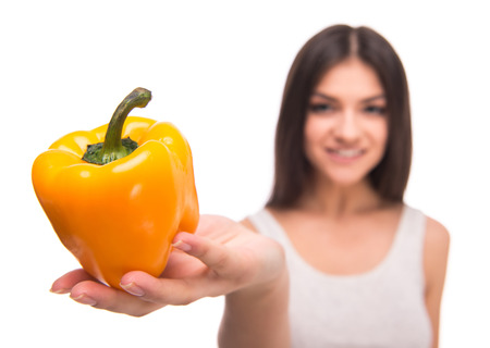 Beautiful young woman is holding a pepper, isolated on white background. Focus on pepper.の写真素材