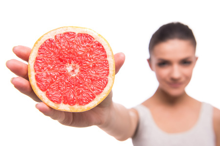 Young woman is holding slices of grapefruits, on white background.の写真素材