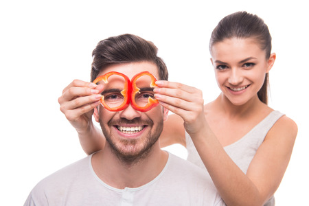 Young woman is holding slices of pepper before the eyes of the boyfriend.の写真素材