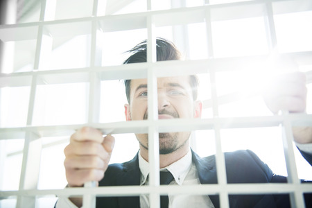 Young businessman is looking at the camera through the grid.の写真素材