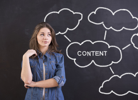 Business concept. Young woman is standing in front of blackboard and looking away.