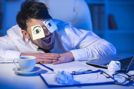 A tired businessman with adhesive note on his eyes.の写真素材
