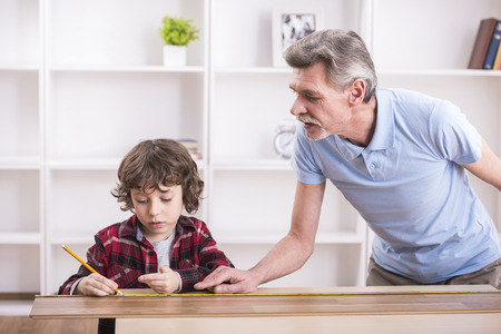 Grandfather and grandson are measuring a table with measuring tape.の写真素材