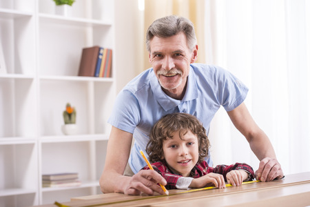 Grandfather and grandson are measuring a table with measuring tape.の写真素材