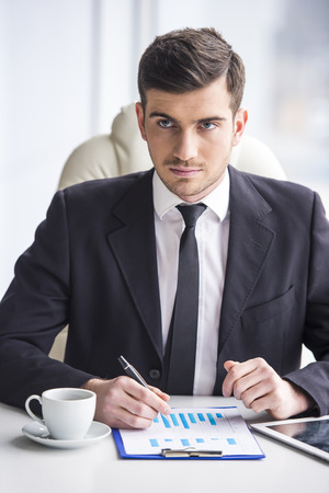 Young businessman is working with papers and drinking coffe.の写真素材