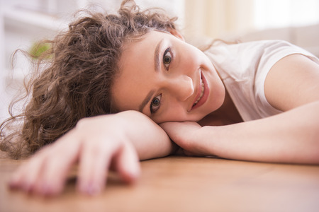 Close-up. Smiling girl is  lying on floor at home. Looking at camera.の写真素材
