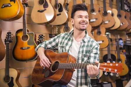 Man is playing on guitar in music shop.の写真素材