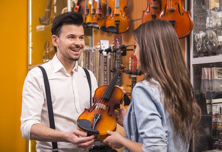 Young girl is buying a violin in the music store.の写真素材