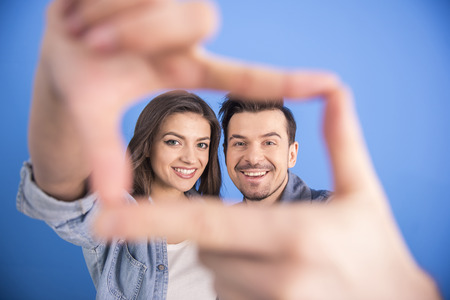 Close-up portrait of a young attractive couple are making a selfie picture isolated on blue background.の写真素材